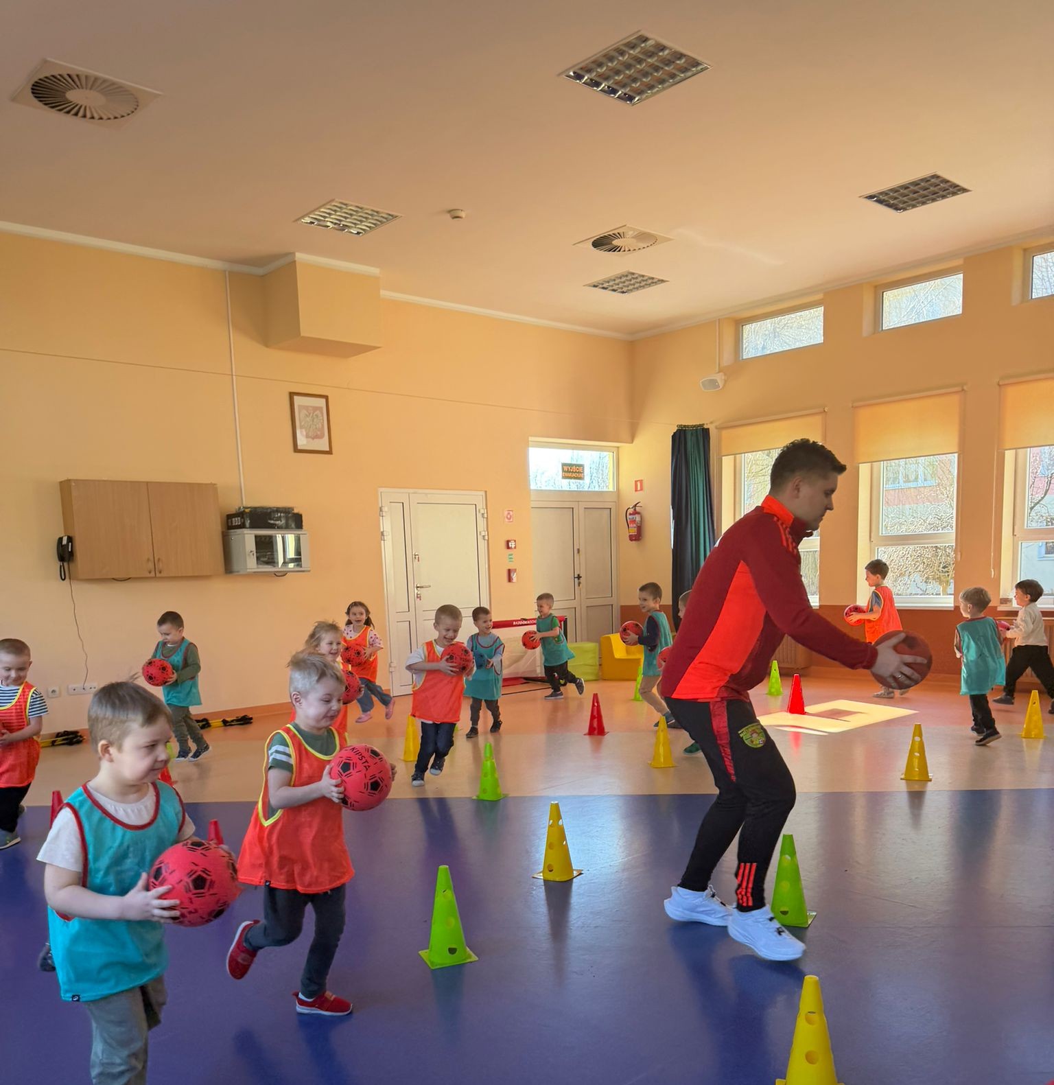 Trener Bartek z grupą dzieci podczas zajęć w przedszkolu